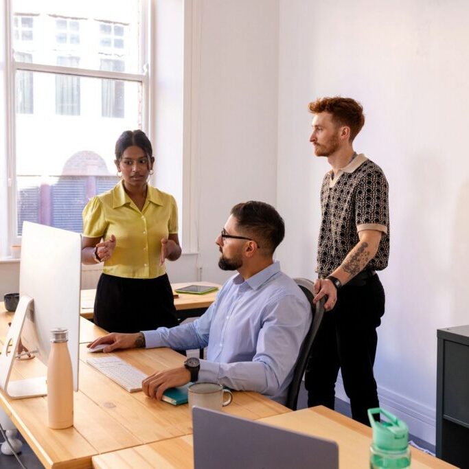 Three colleagues discussing work in office.
